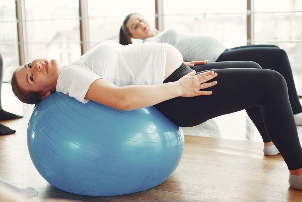 Schwangere Frauen beim gelenkschonenden Training mit Fitnessbällen in Innenräumen.