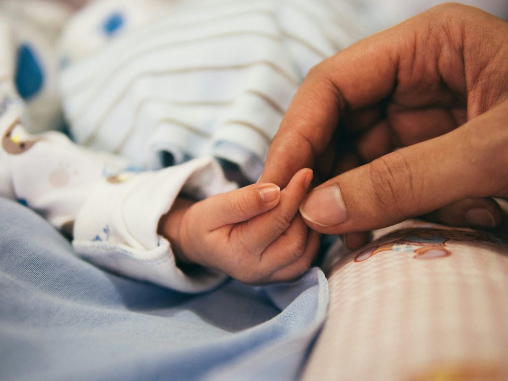 Person, die den Zeigefinger eines Babys hält